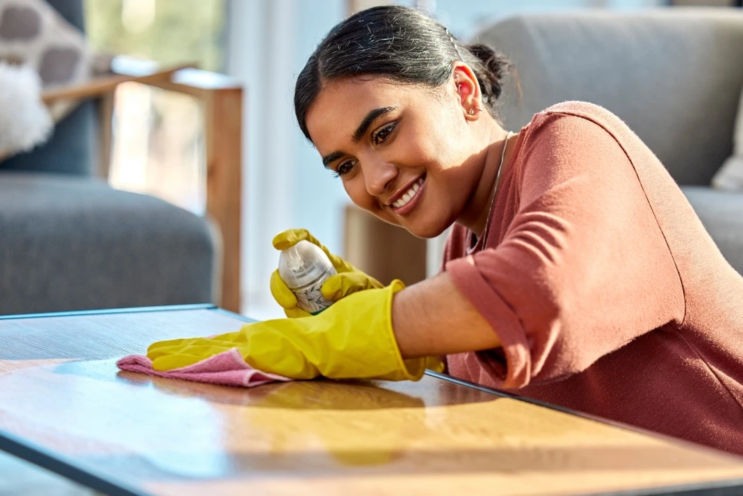 Woman cleaning coffee table at home