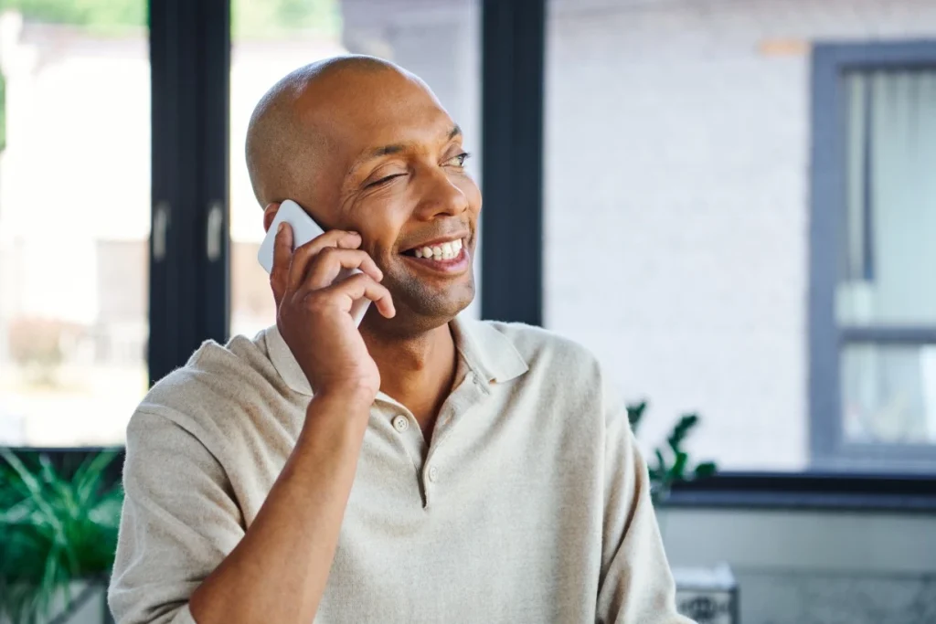 Happy disabled man using mobile phone to contact I.B Care