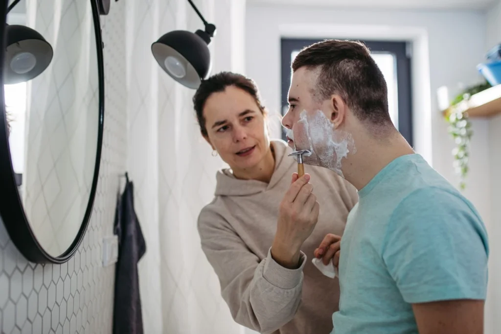 Support worker helping disabled man with down syndrome shave face