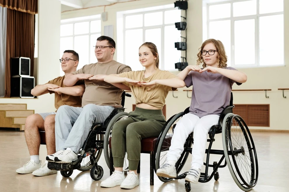 Group of disabled friends in wheelchairs and with invisible disabilities in group dance class