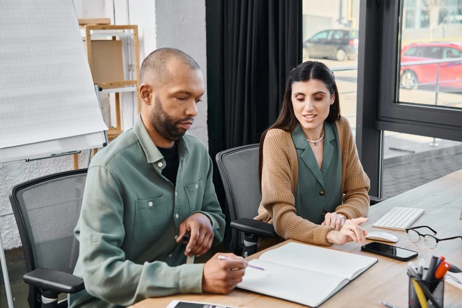 Disabled man in office with support worker writing in notepad